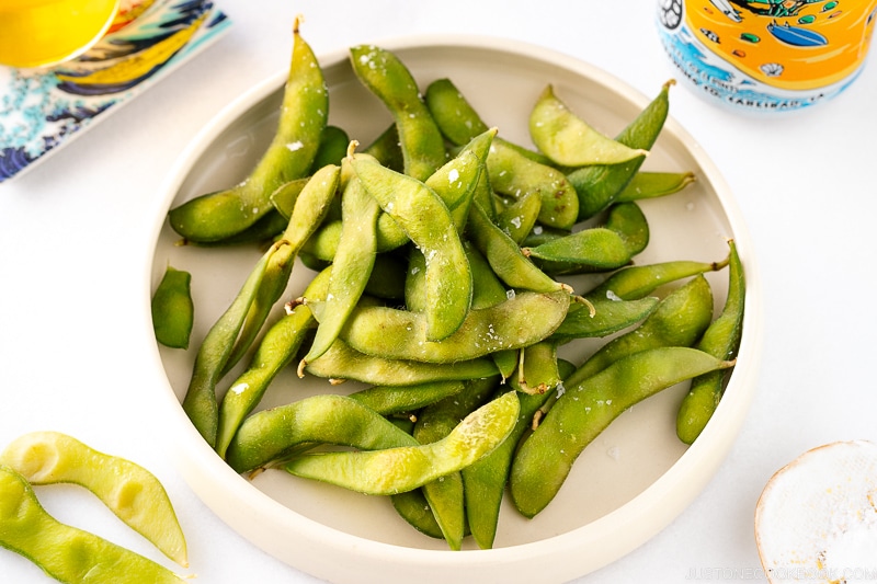 A white ceramic plate containing Edamame.