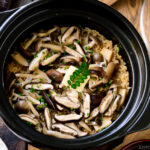 A Hario donabe (Japanese clay pot) containing Japanese Mushroom Rice topped with butter, chives, and sea salt flakes.