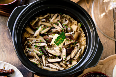 A Hario donabe (Japanese clay pot) containing Japanese Mushroom Rice topped with butter, chives, and sea salt flakes.