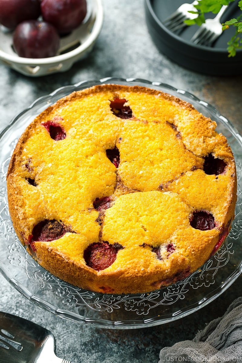 A whole plum cake on the glass cake stand.