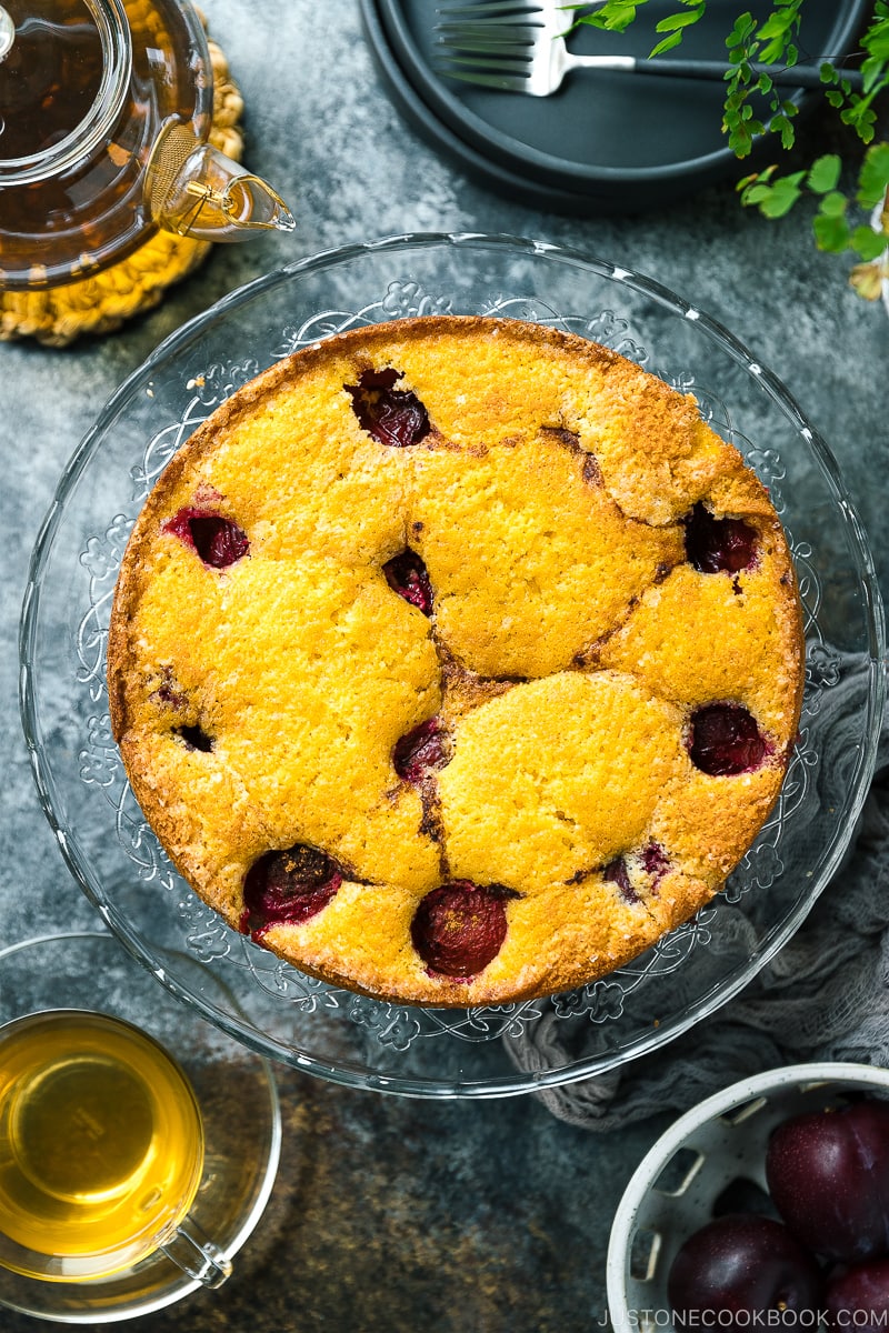 A whole plum cake on the glass cake stand.