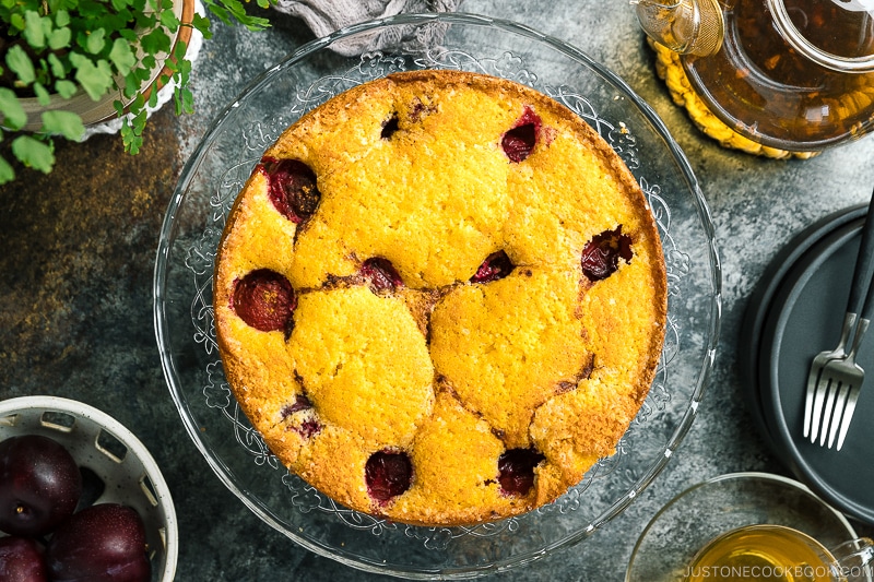 A whole plum cake on the glass cake stand.