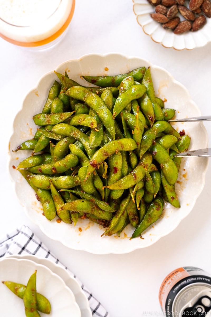 A white ceramic plate containing spicy edamame.