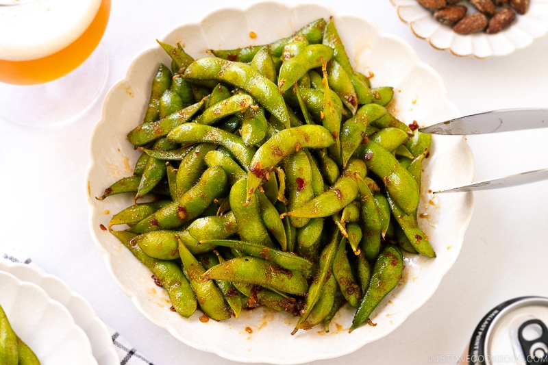 A white ceramic plate containing spicy edamame.