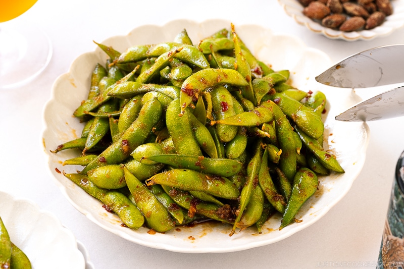 A white ceramic plate containing spicy edamame.