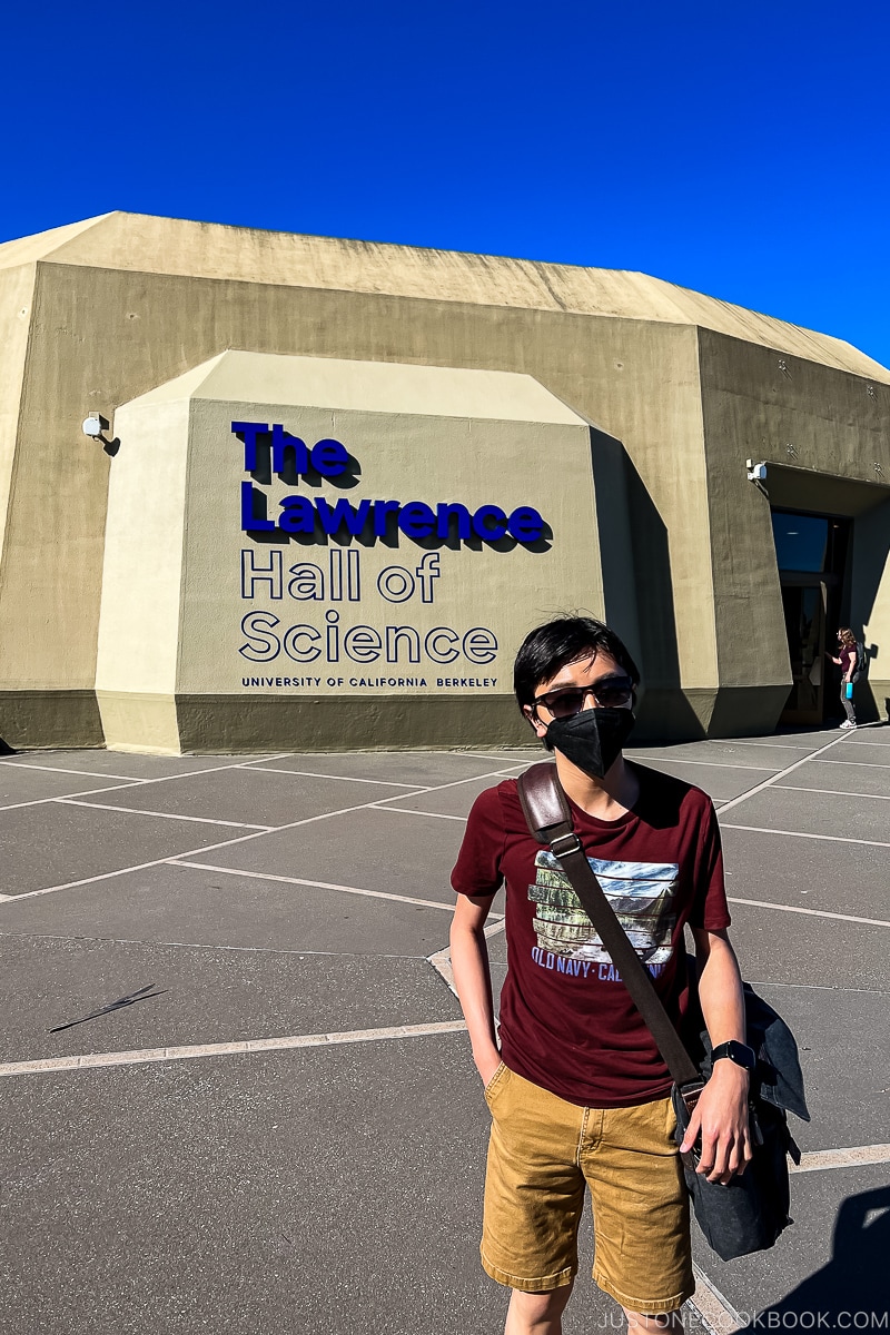 a boy standing in front of The Lawrence Hall of Science