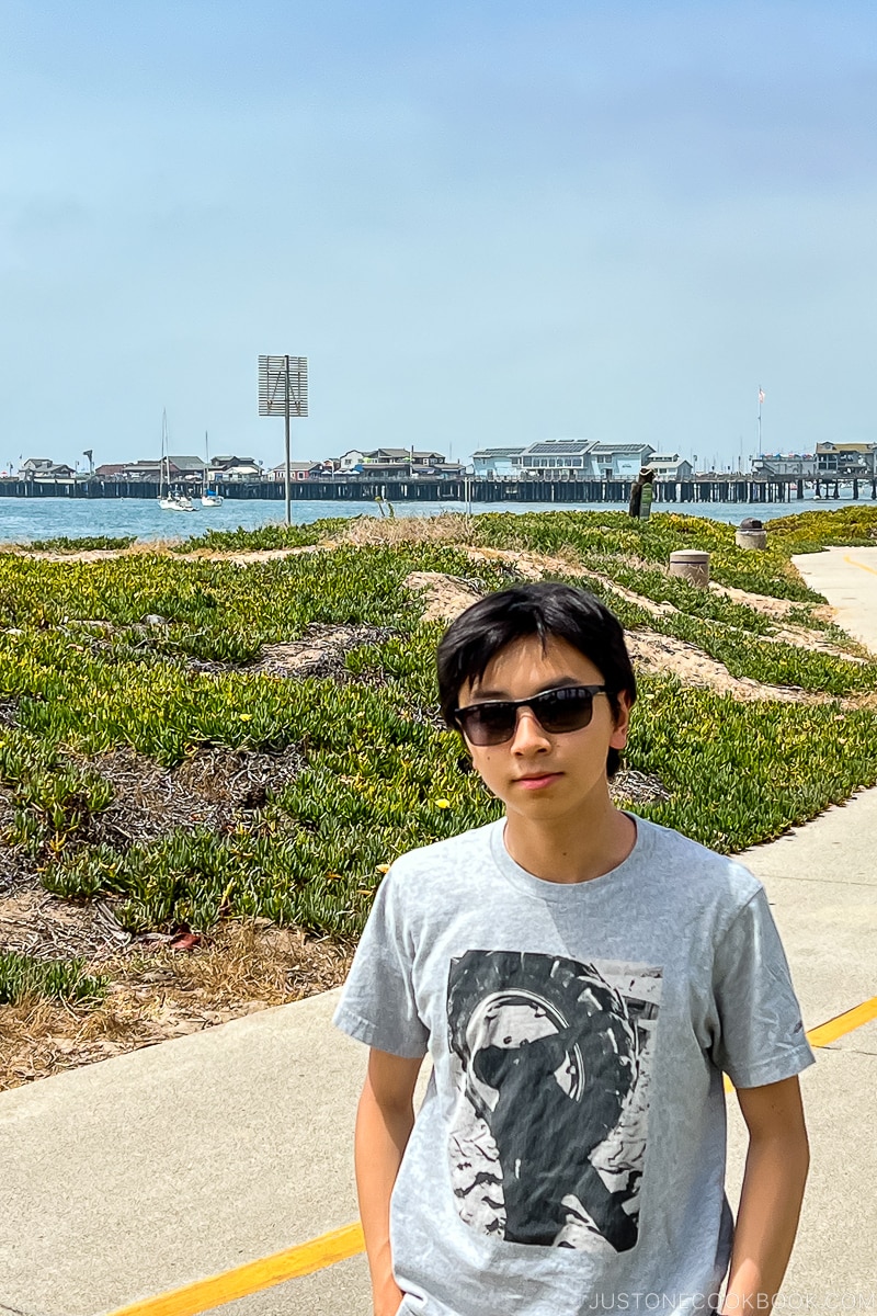 a boy standing on bike path near the ocean