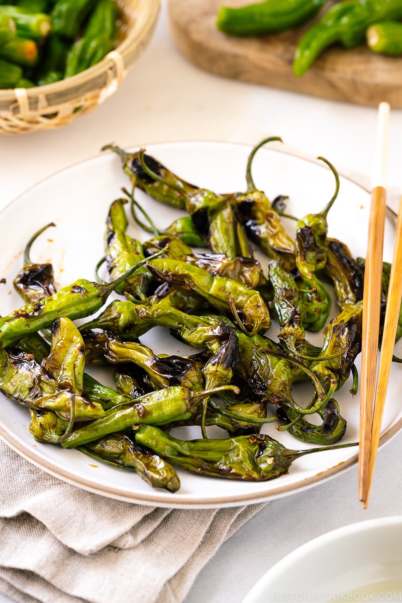 A white plate containing Blistered Shishito Peppers With Ginger Soy Sauce.