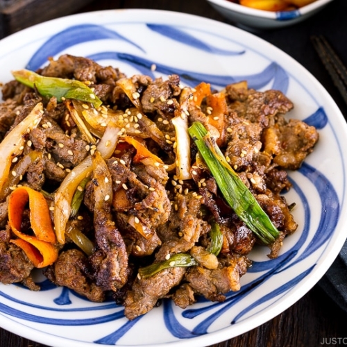 A blue and white Japanese plate containing Bulgogi (Korean grilled beef).