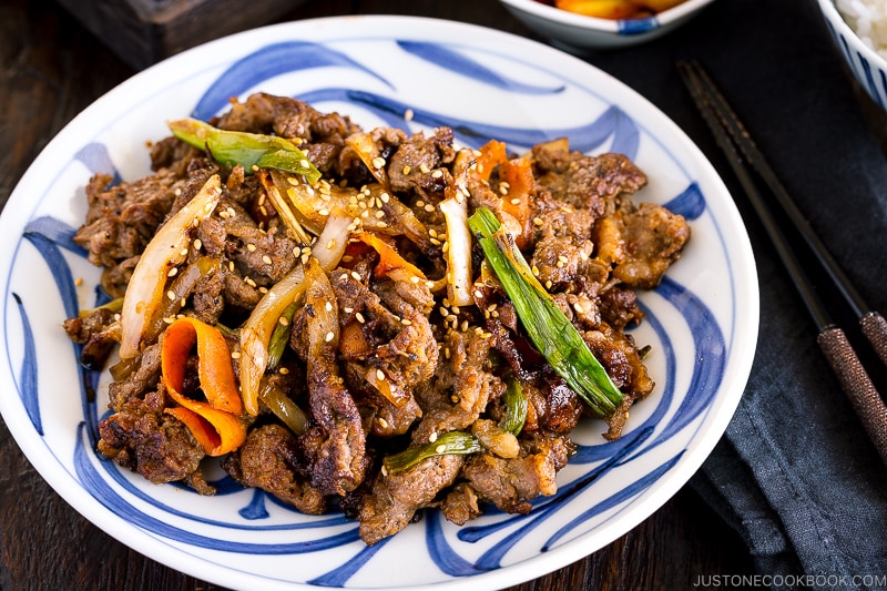 A blue and white Japanese plate containing Bulgogi (Korean grilled beef).