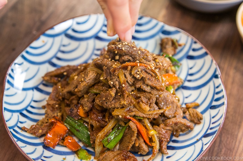 A blue and white Japanese plate containing Bulgogi (Korean grilled beef).