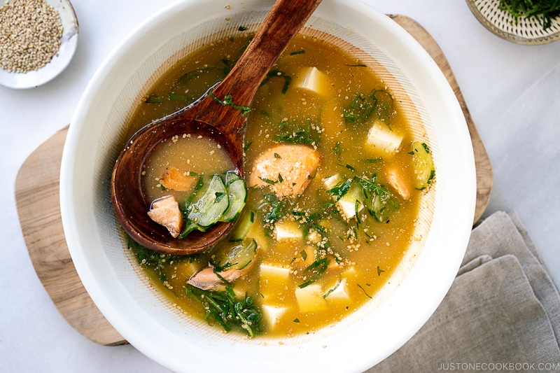 A white Japanese bowl containing cold miso soup (hiyajiru) with tofu, cucumber, and salmon).