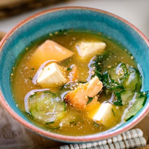 A cobalt blue ceramic bowl containing cold miso soup (hiyajiru) with tofu, cucumber, and salmon).