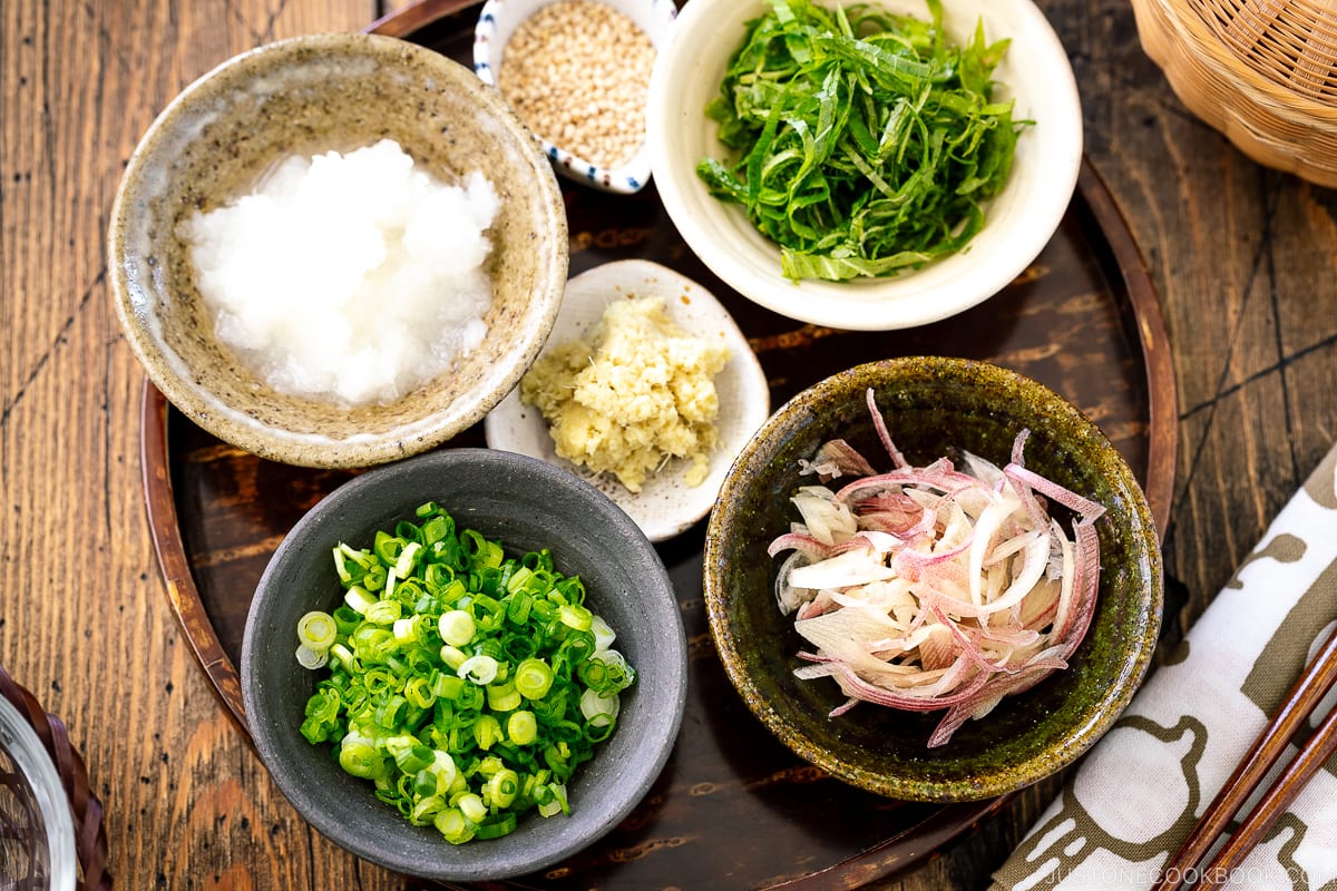 A tray containing multiple small bowls containing garnishes for the somen noodles.