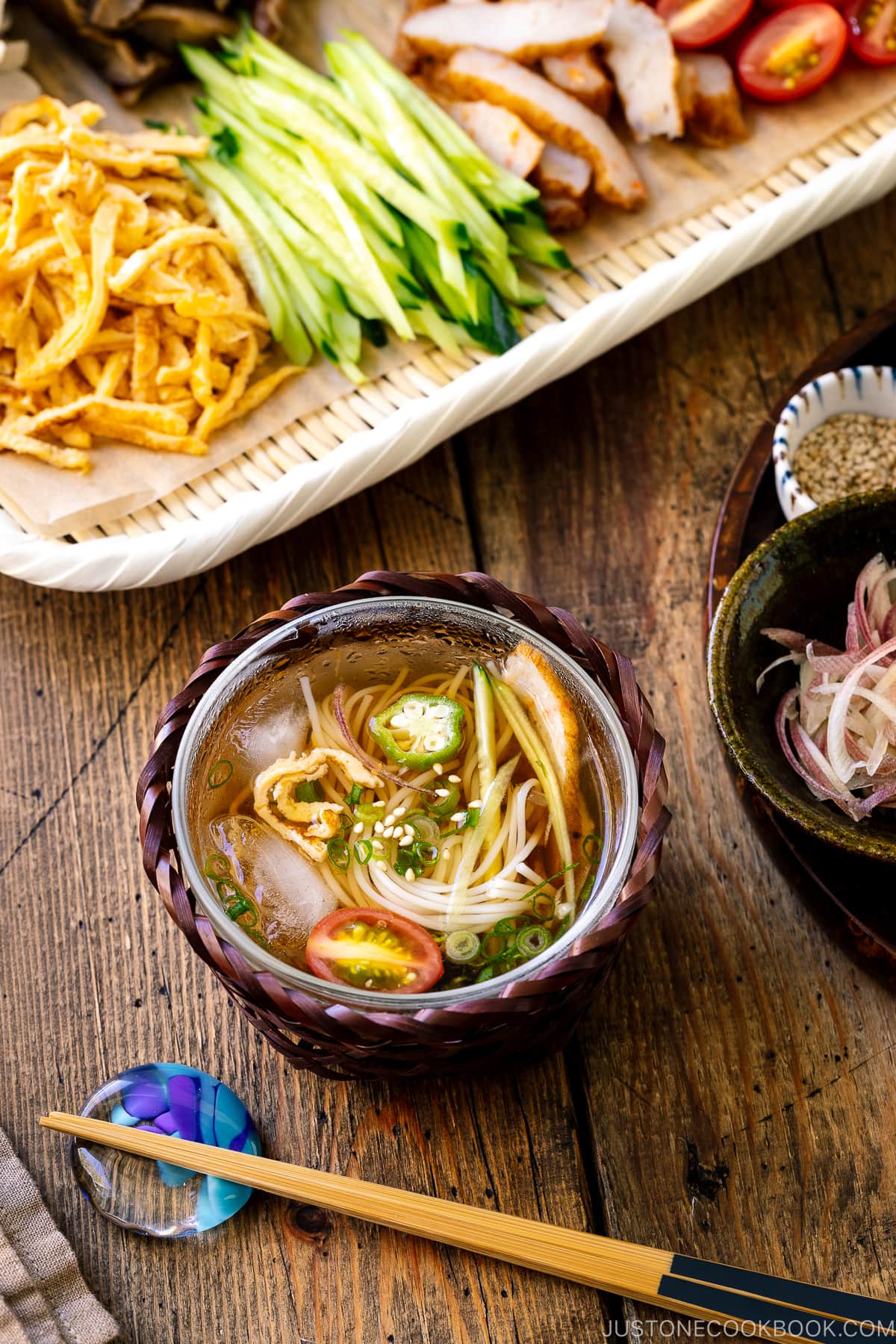 A glass bowl containing cold somen noodles with dipping sauce.