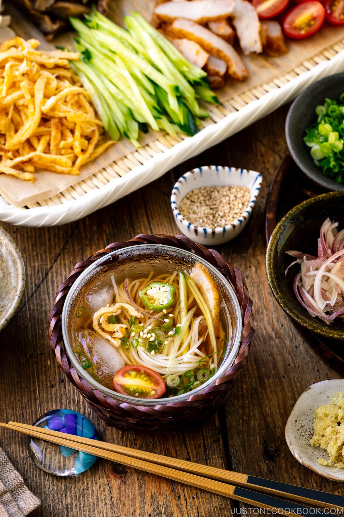 A glass bowl containing cold somen noodles with dipping sauce.