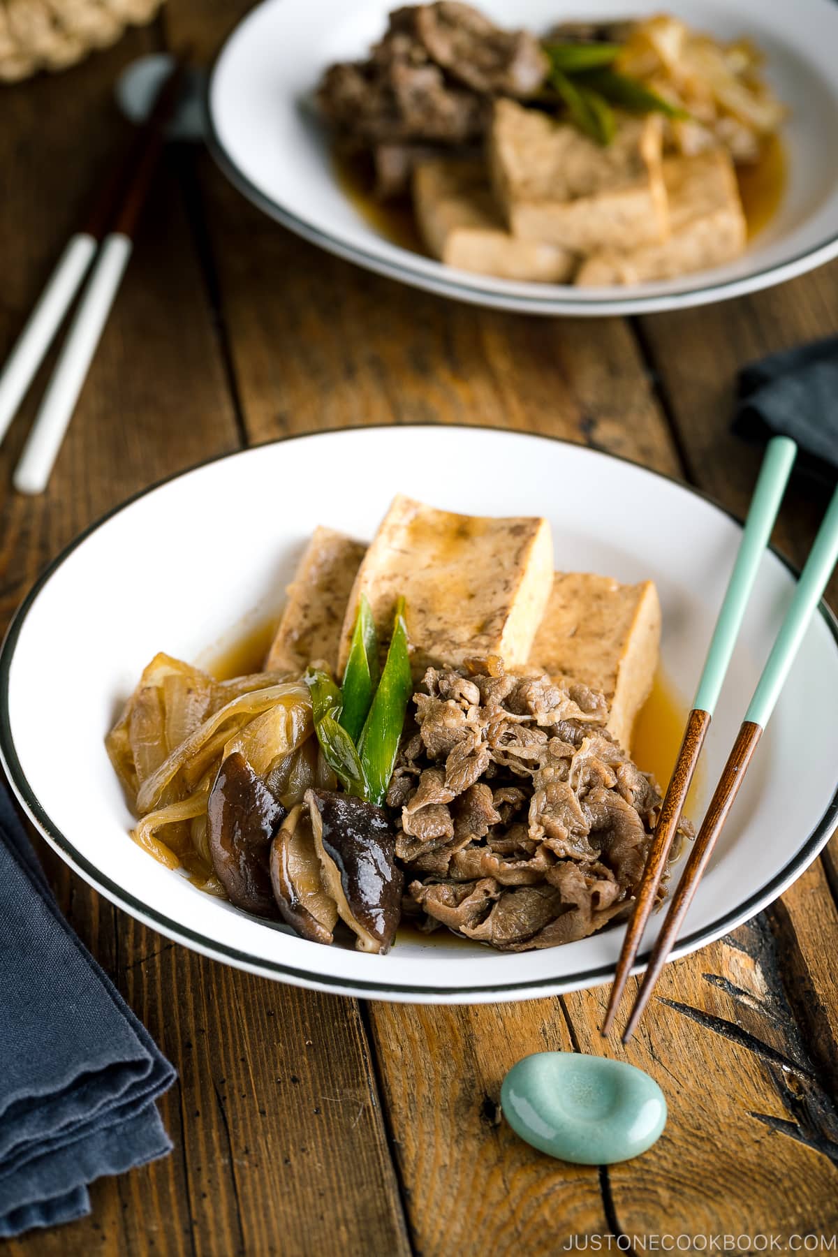 A white plate containing Japanese simmered beef and tofu (niku dofu).