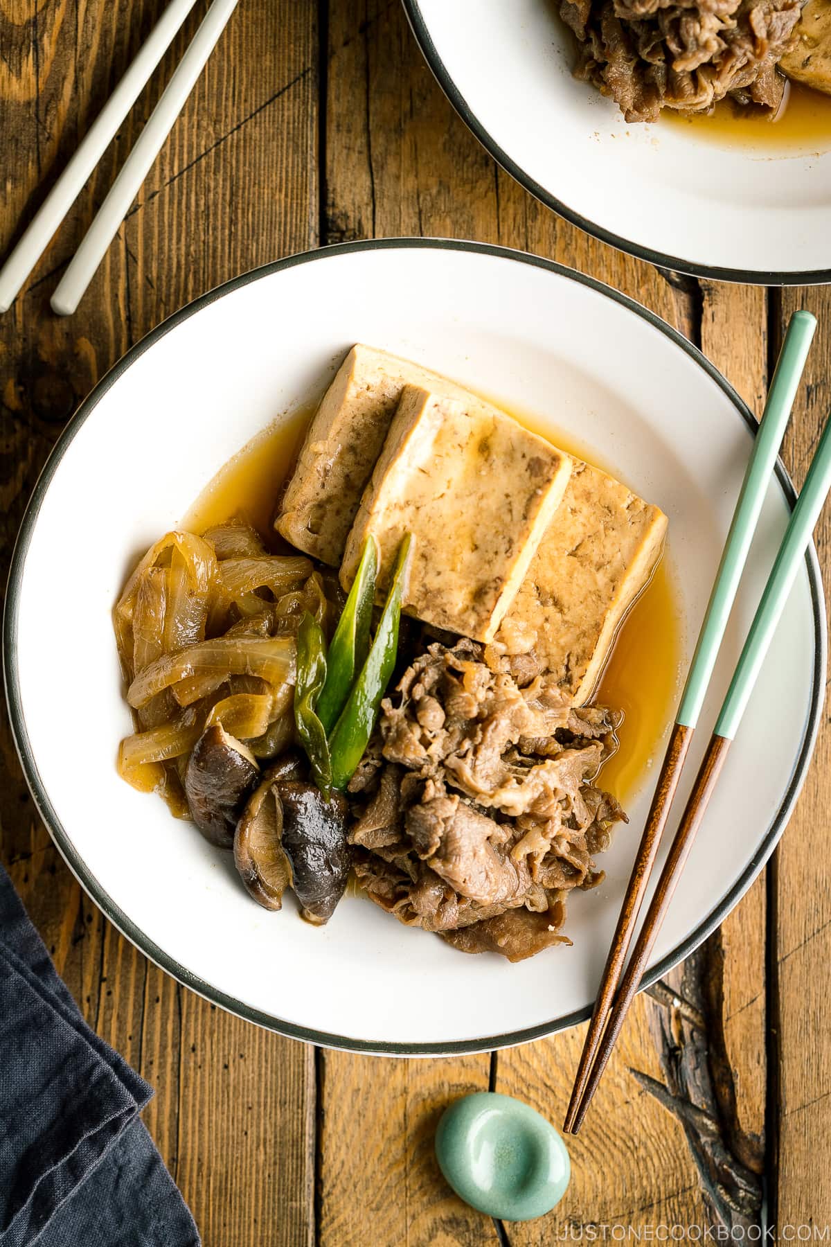 A white plate containing Japanese simmered beef and tofu (niku dofu).