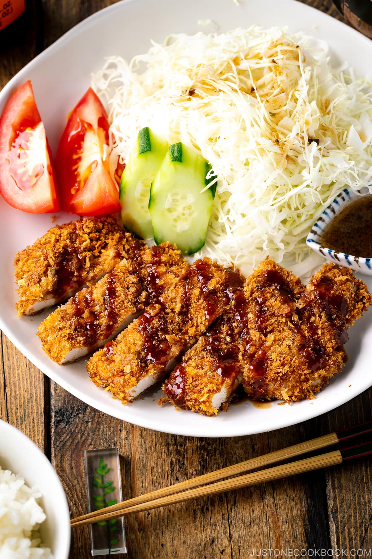 A white plate containing Baked Chicken Katsu (Japanese Chicken Cutlets) and shredded cabbage salad.