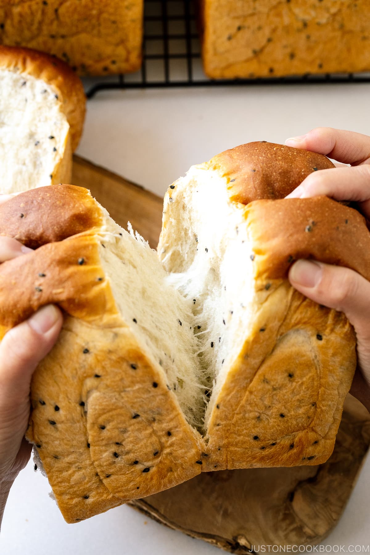 Tearing a loaf of Black Sesame Shokupan (Japanese Milk Bread) with hands.