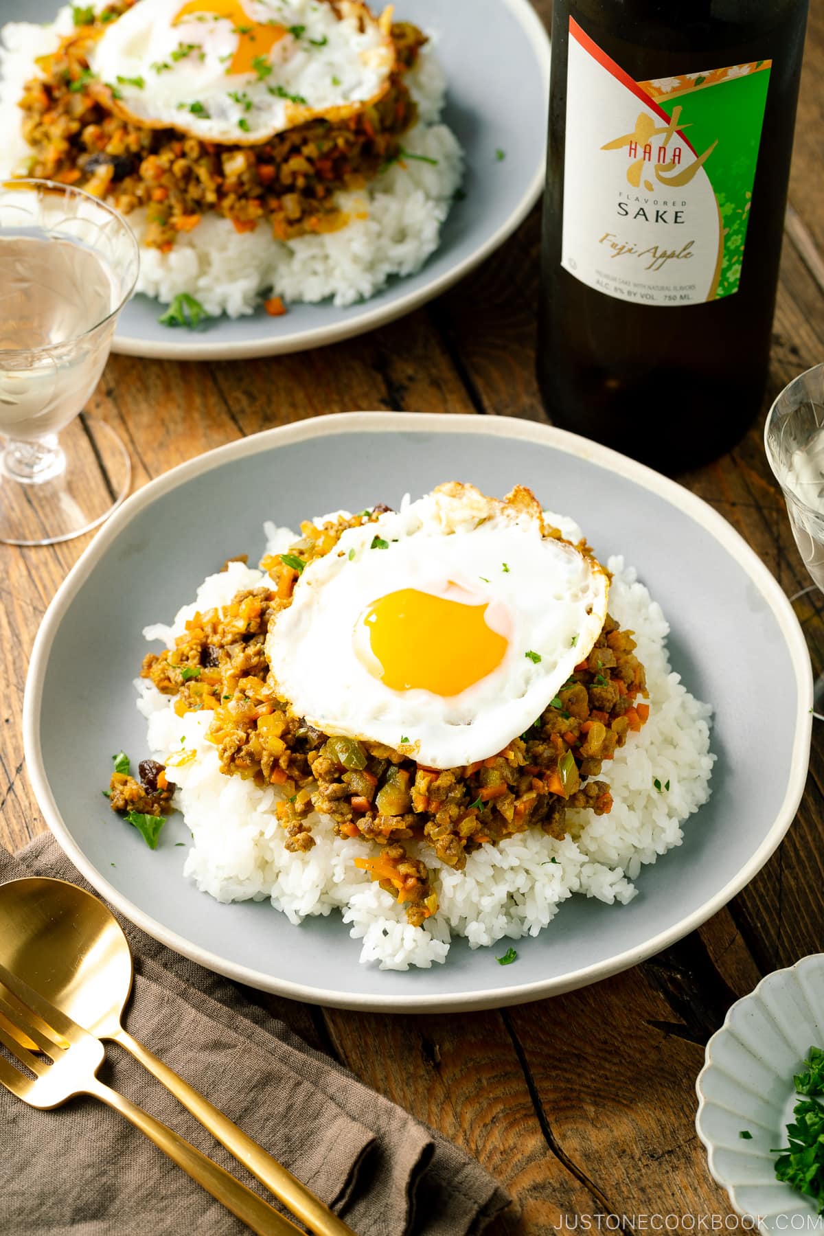 A ceramic plate containing steamed rice, dry curry, and a fried egg.