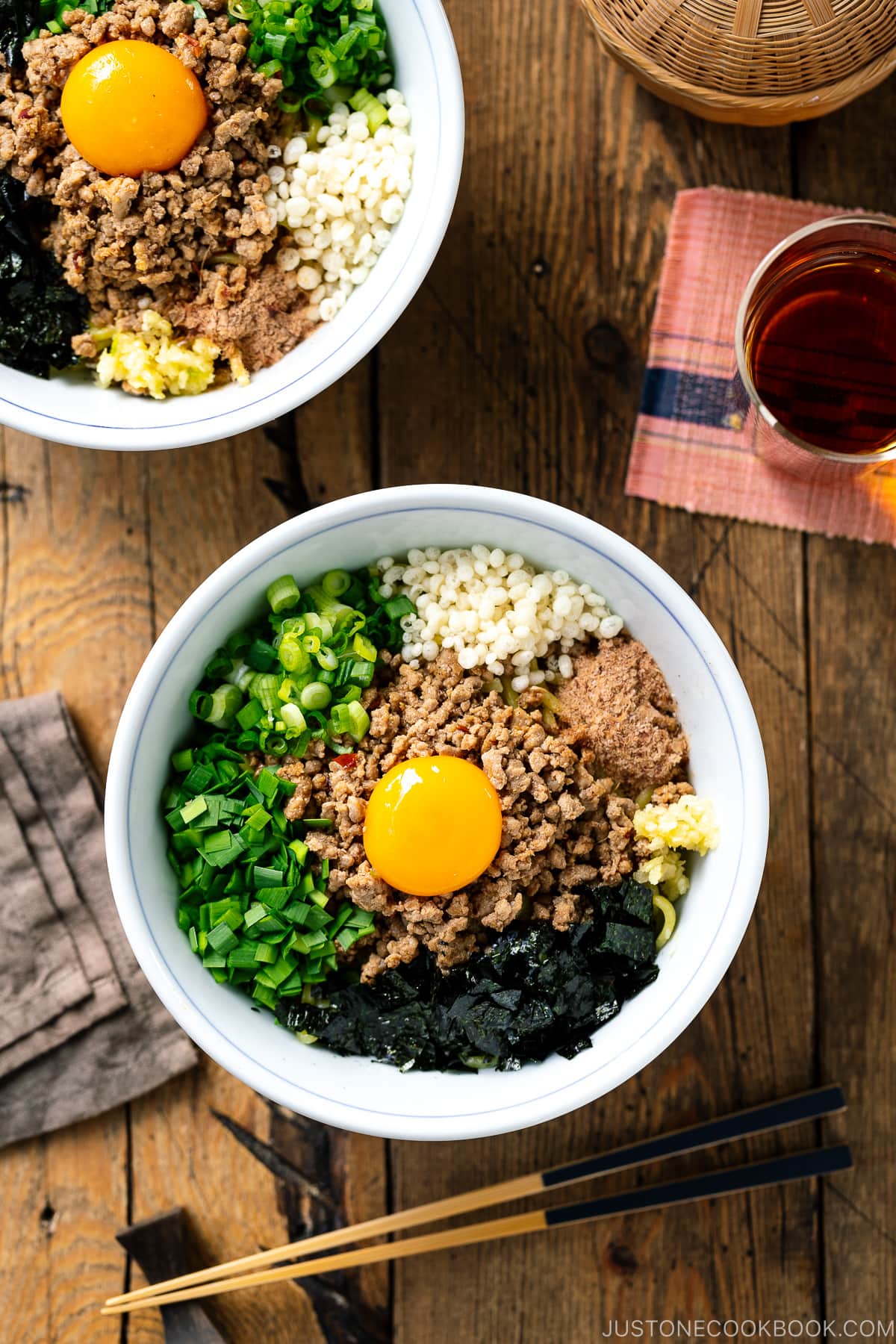 A bowl containing Mazesoba (Mazemen), Japanese Brothless Ramen, topped with seasoned minced meat, green onion, garlic chives, nori seaweed, crushed garlic, and katsuobushi powder.