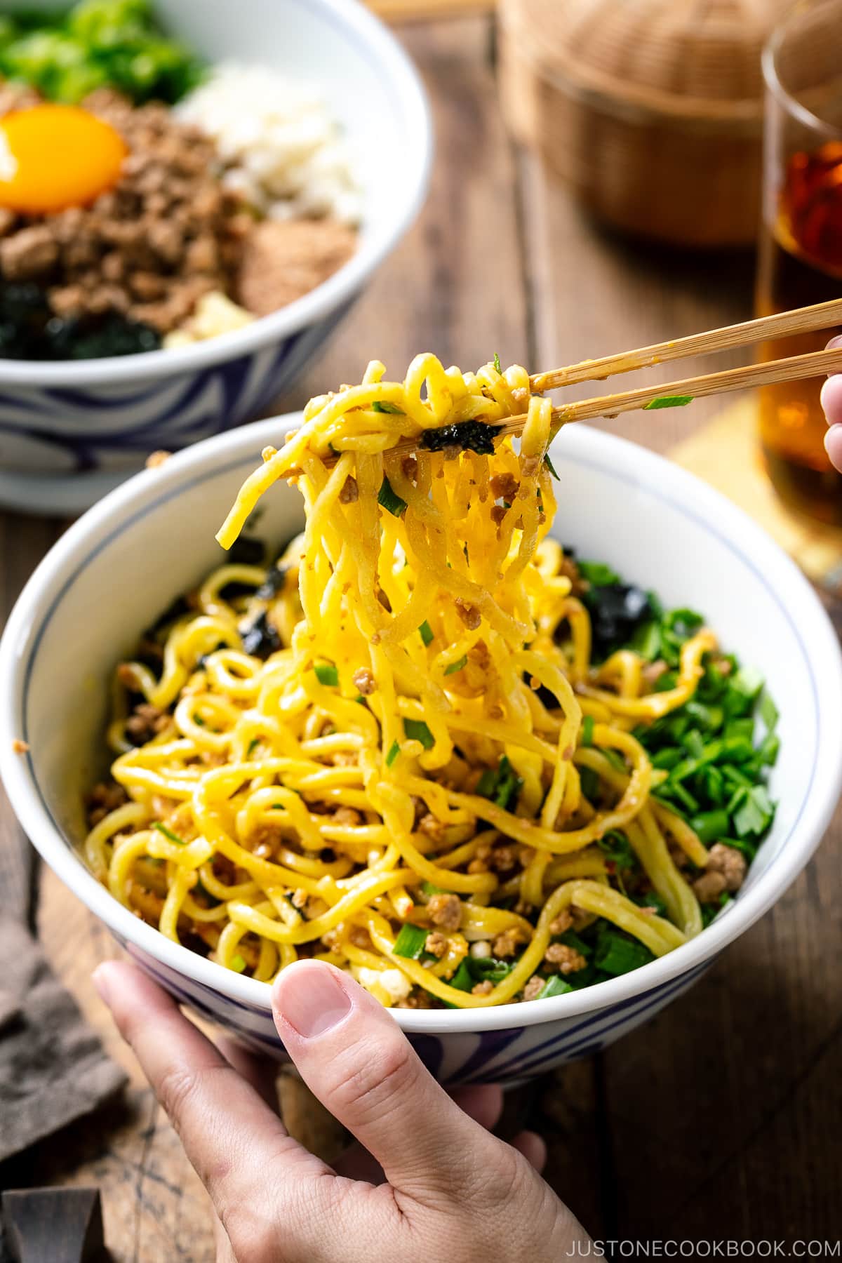 Chopsticks picking up Mazesoba (Mazemen), Japanese Brothless Ramen, from the bowl.