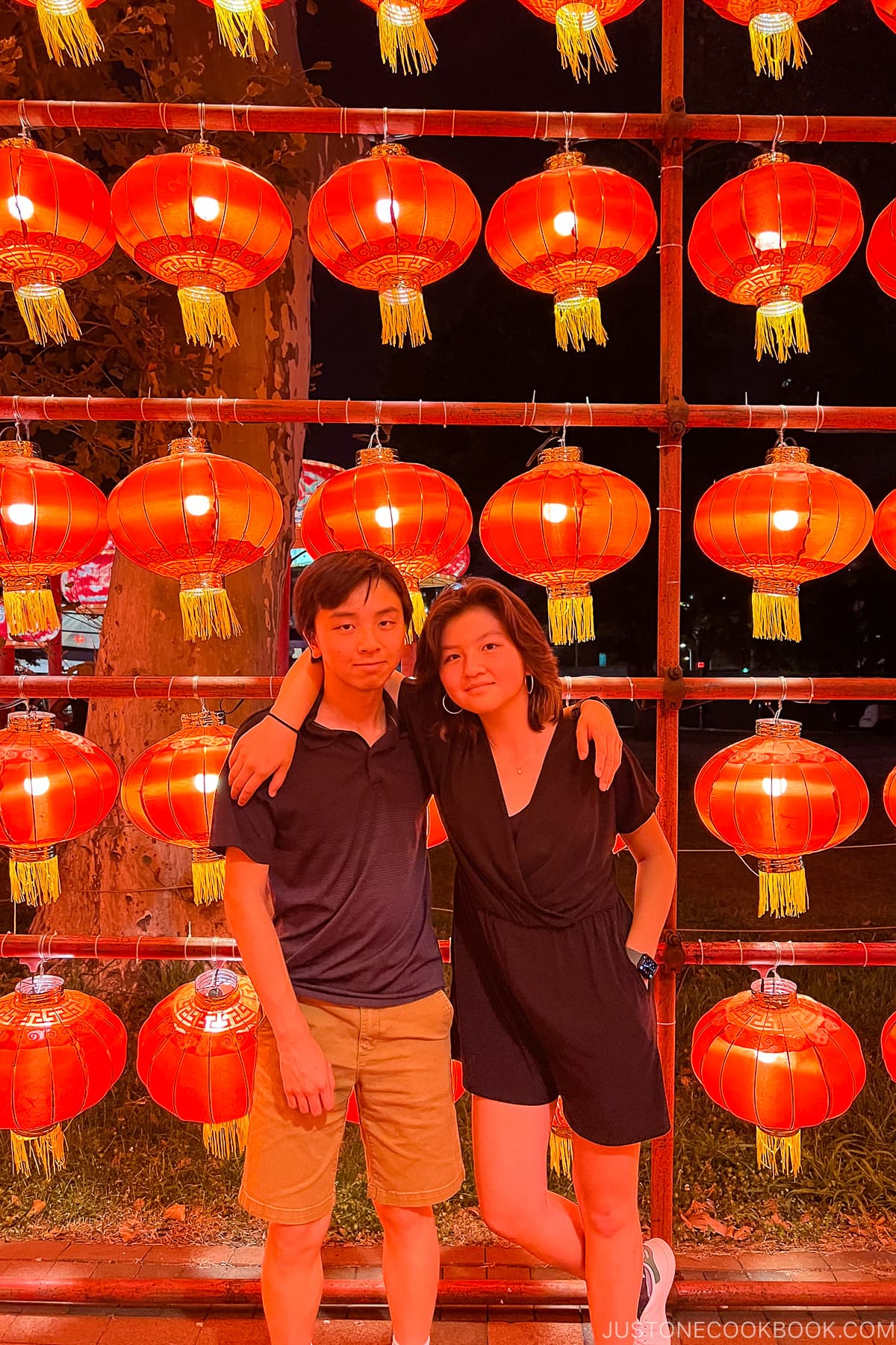 a boy and girl standing in front of lantern