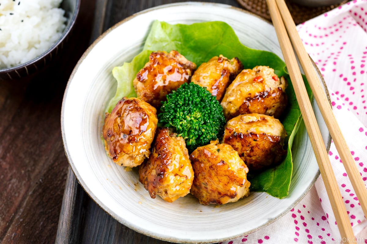 A white bowl containing teriyaki chicken meatballs and broccoli.