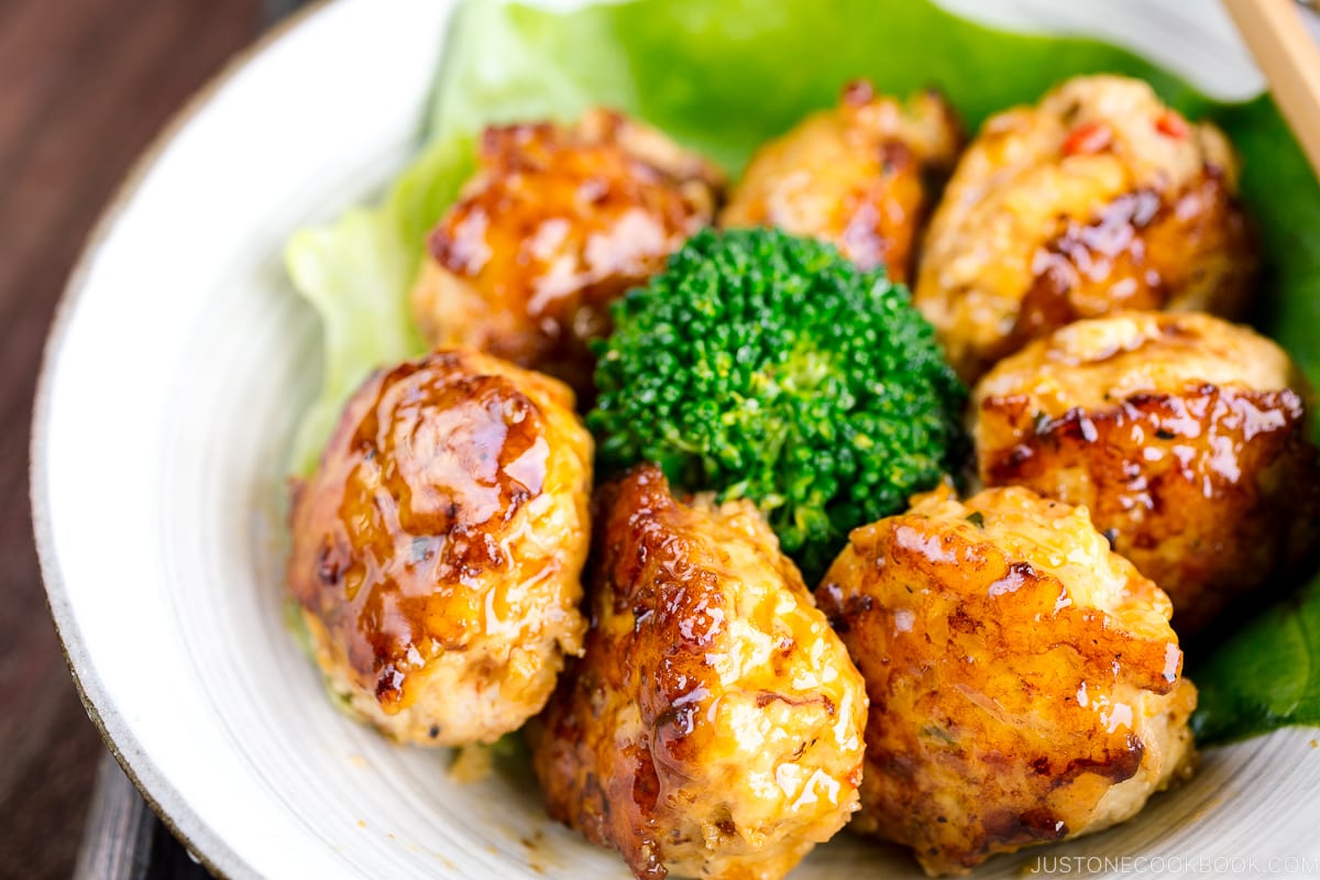 A white bowl containing teriyaki chicken meatballs and broccoli.