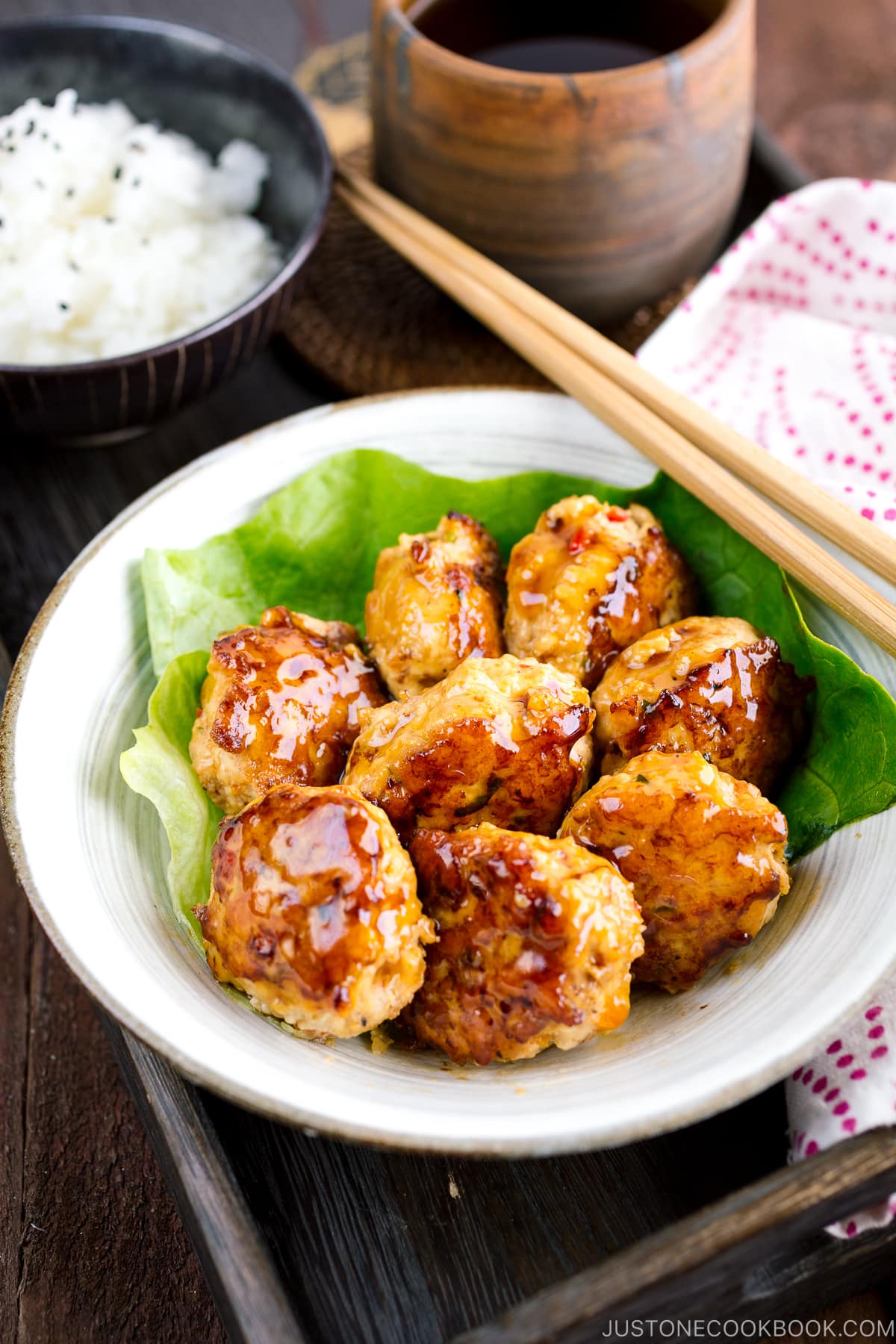 A white bowl containing teriyaki chicken meatballs and broccoli.