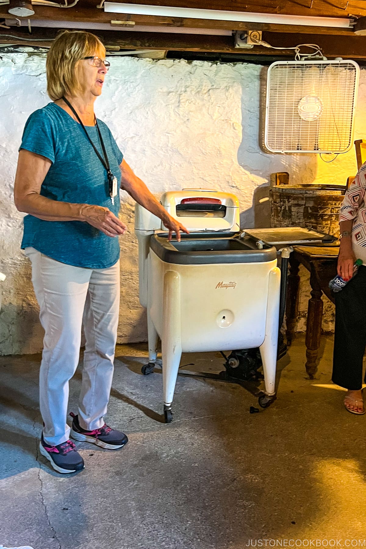 a women standing next to an antique washing machine