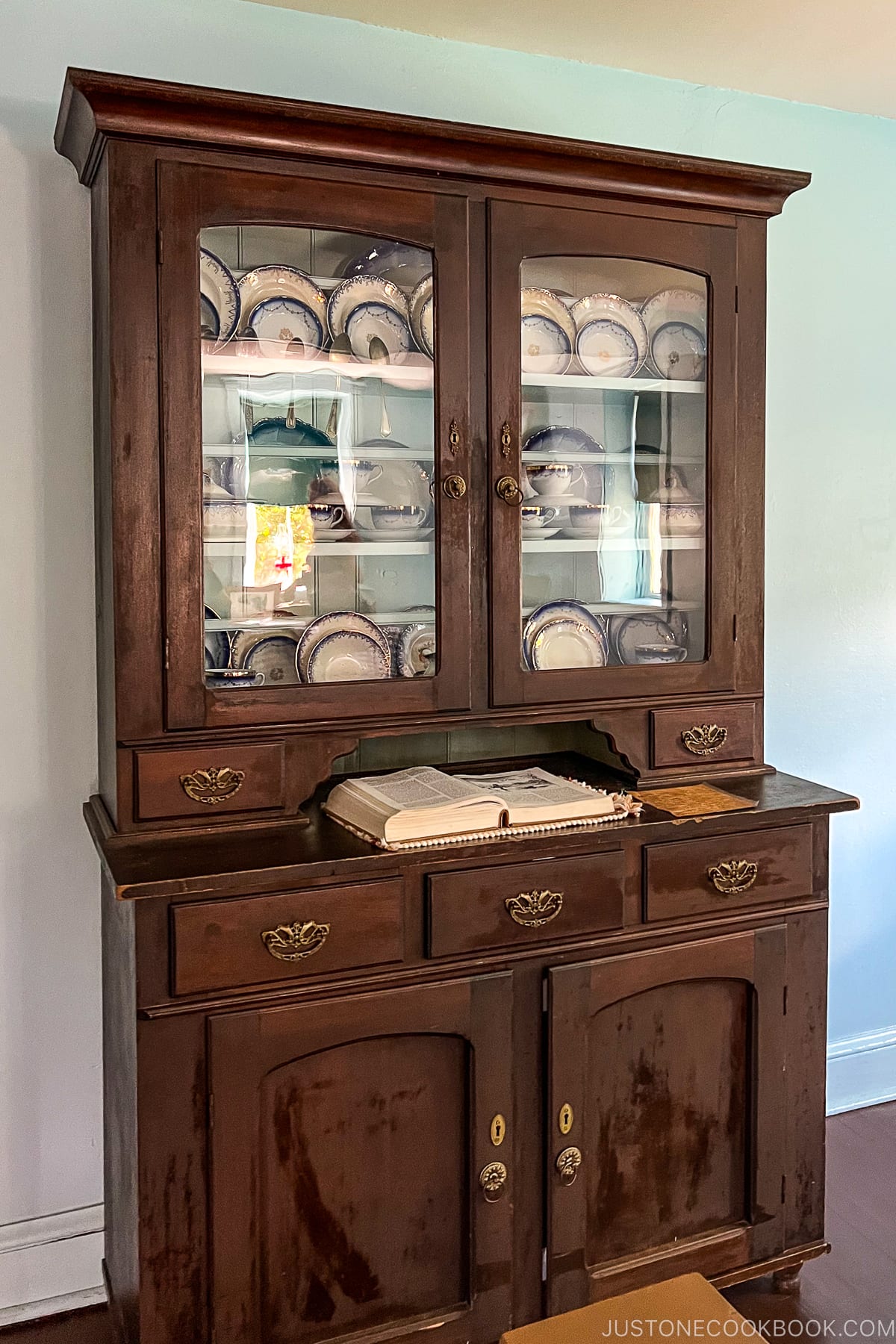 a wood cabinet with dishes in the display case