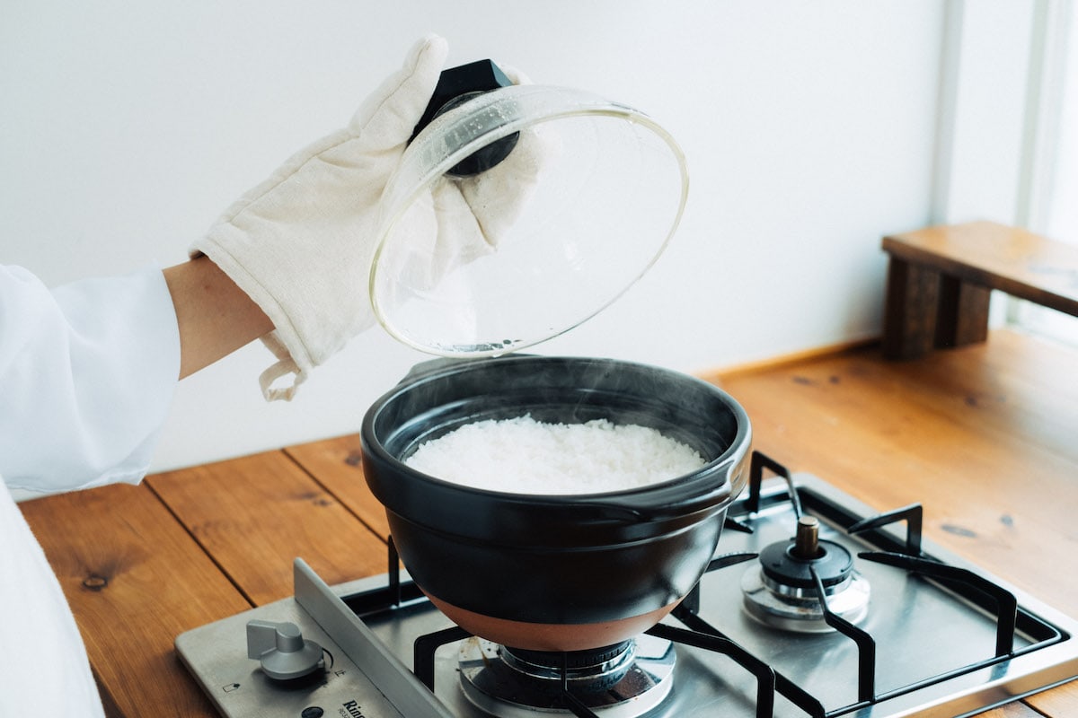 Rice paddle scooping rice out of the kamadosan donabe containing perfectly cooked Japanese rice.