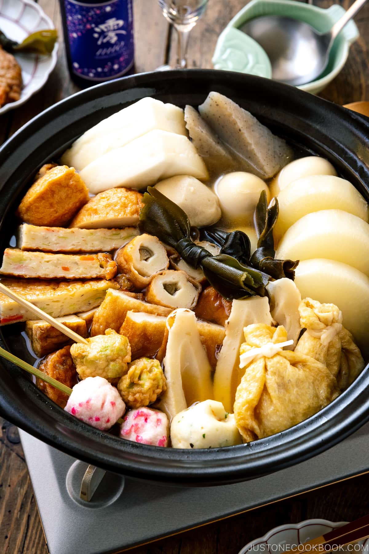 A donabe clay pot containing Japanese fish cake stew called oden, an assortment of fish balls and fish cakes.
