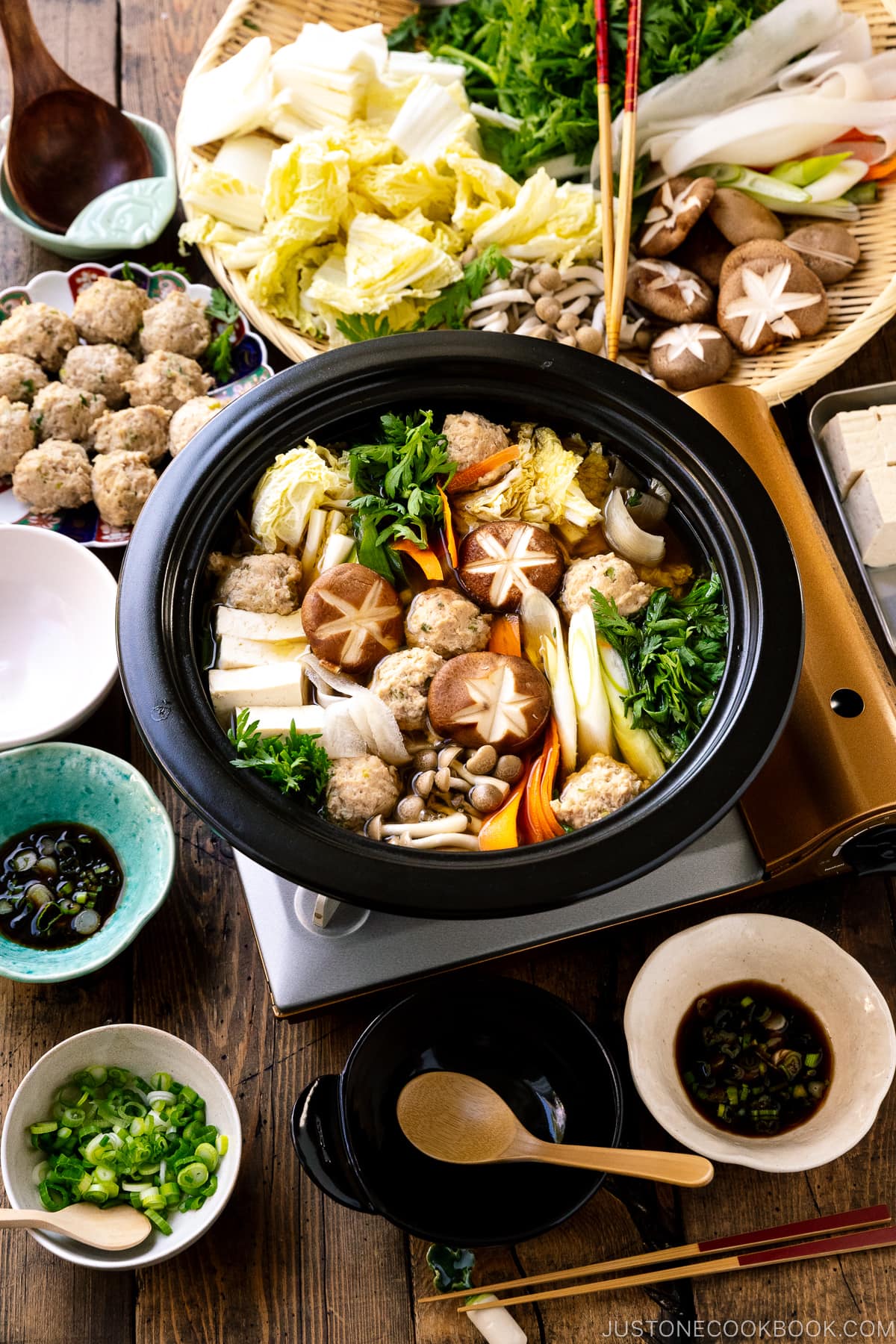 A Japanese clay pot simmering chicken meatballs, tofu, mushrooms, and various vegetables in a savory dashi broth.