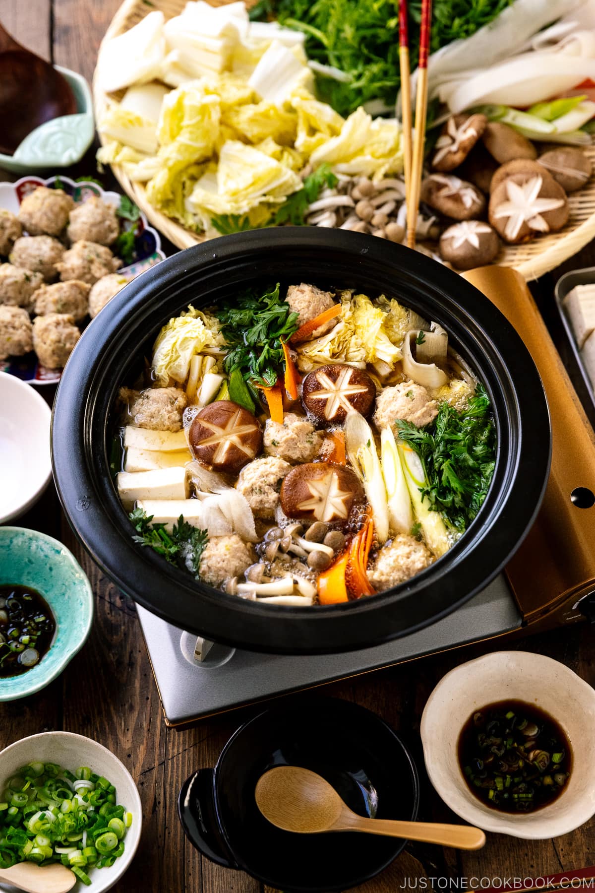 A Japanese clay pot simmering chicken meatballs, tofu, mushrooms, and various vegetables in a savory dashi broth.