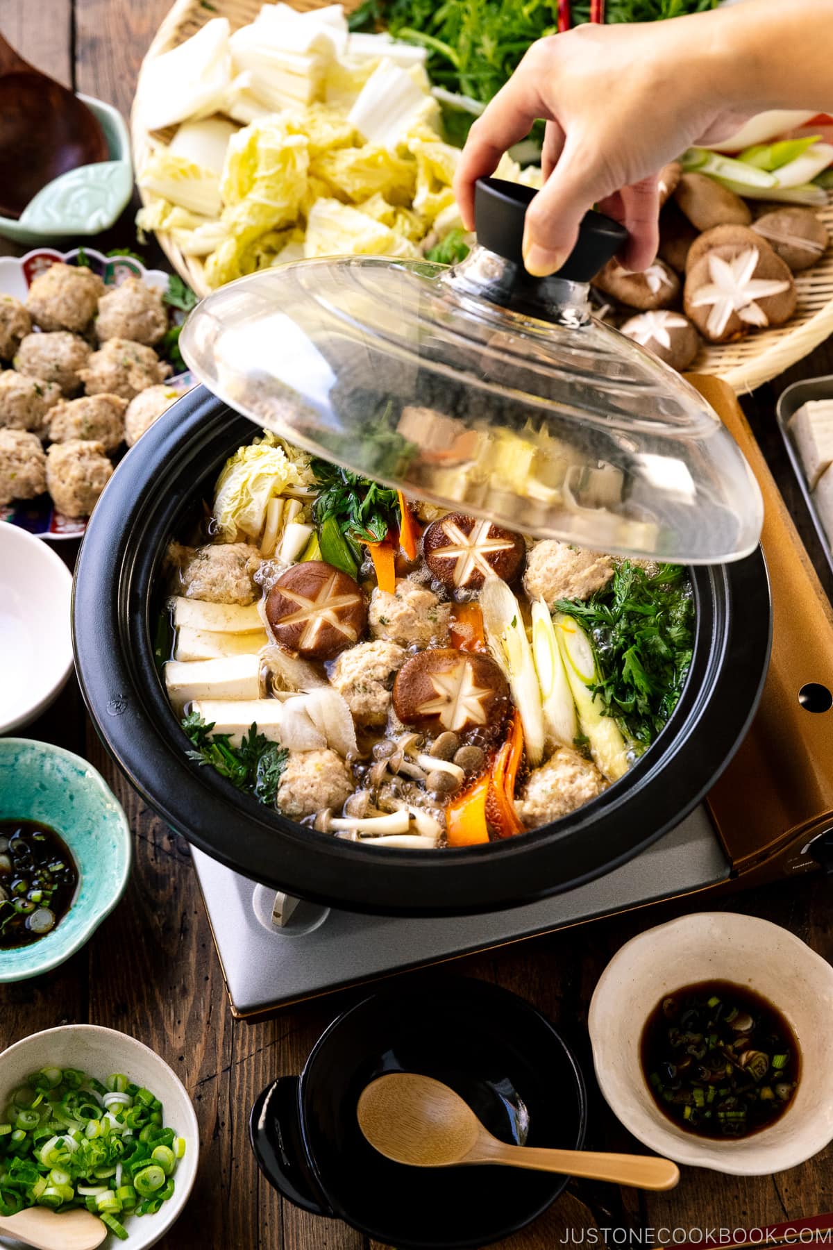 A Japanese clay pot simmering chicken meatballs, tofu, mushrooms, and various vegetables in a savory dashi broth.