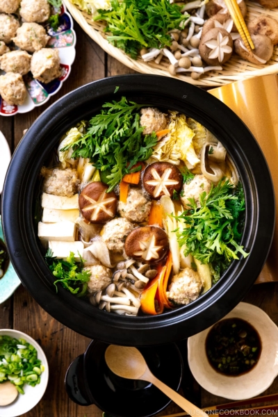 A Japanese clay pot simmering chicken meatballs, tofu, mushrooms, and various vegetables in a savory dashi broth.