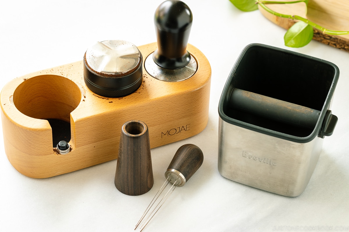 coffee whisk, knock box, tamper on a marble table