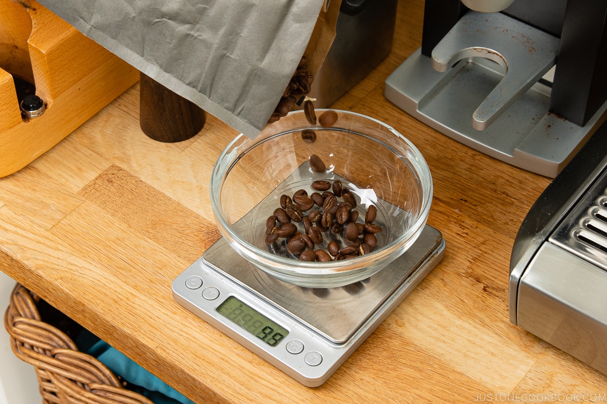 grãos de café sendo despejados em uma tigela de vidro