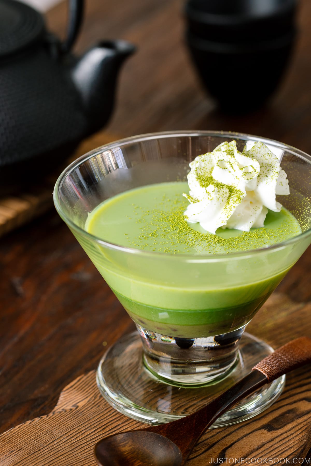 Un verre contenant du pudding au matcha avec de la crème fouettée.