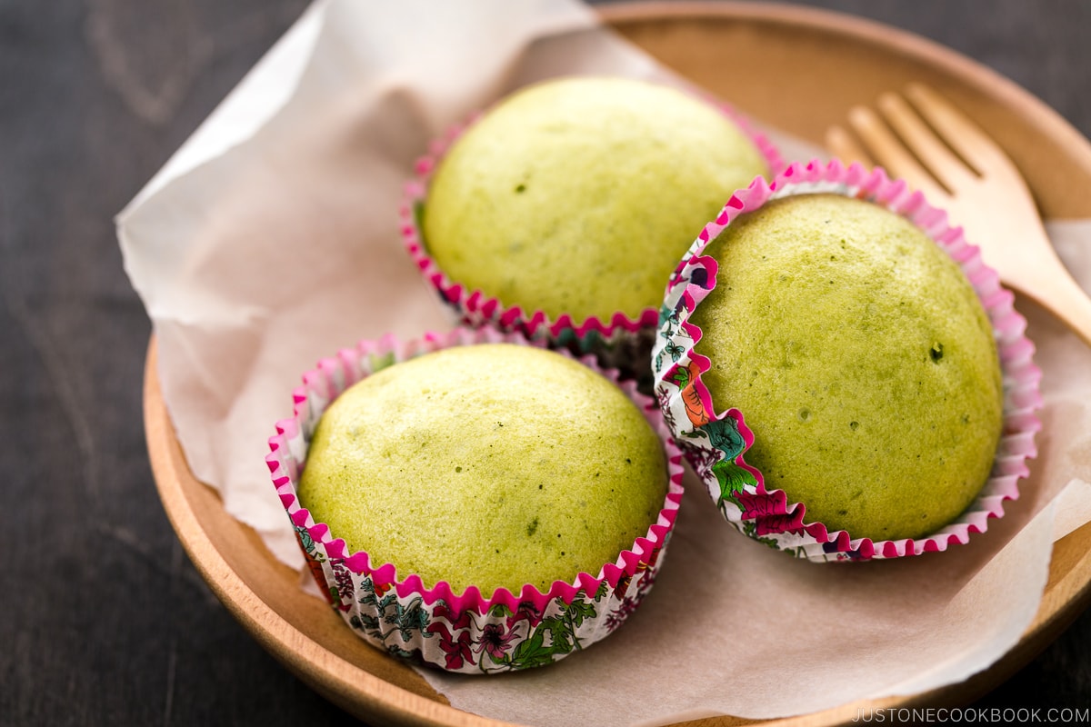 A wooden plate containing matcha green tea steamed cakes.