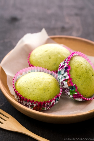 A wooden plate containing matcha green tea steamed cakes.