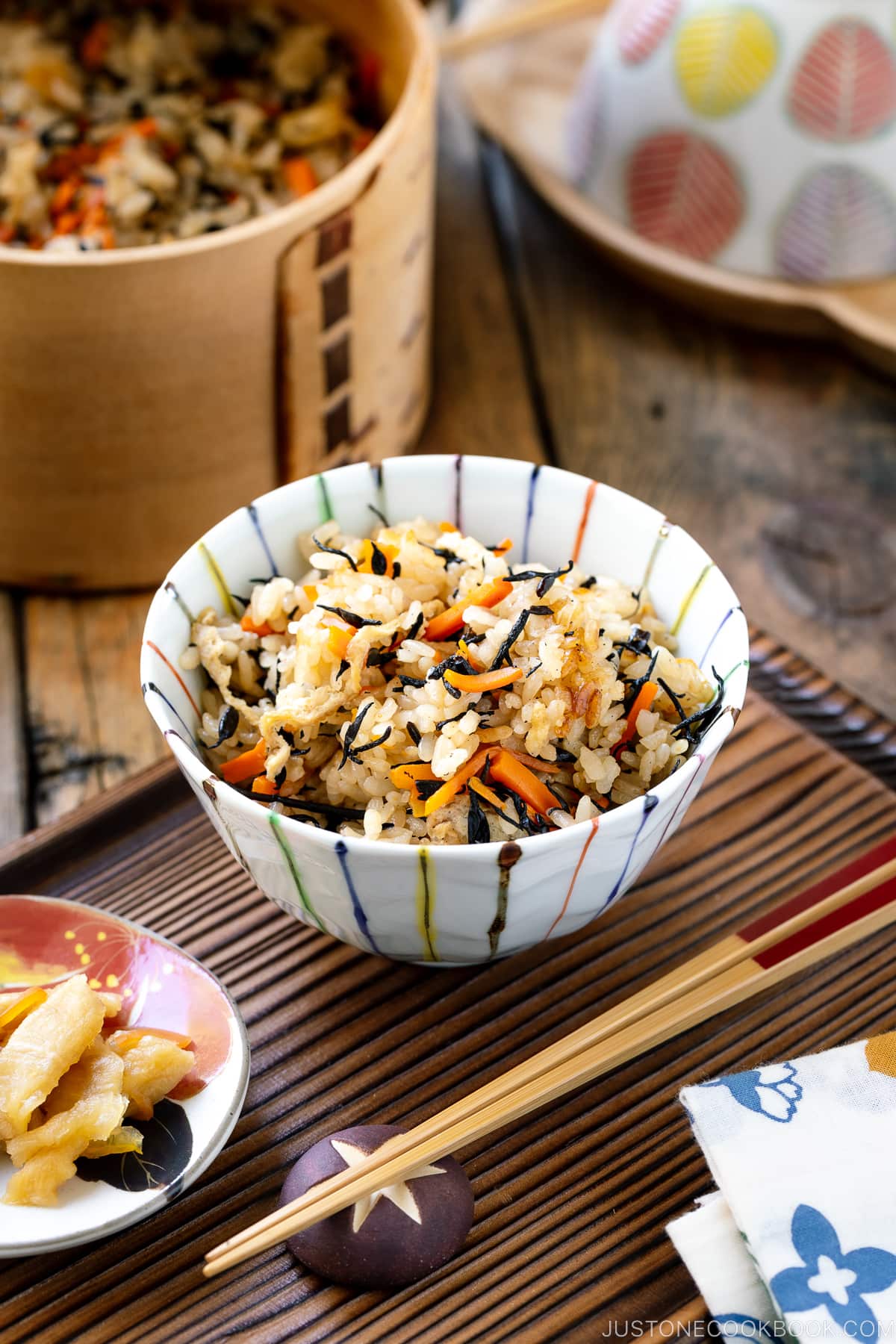 Un bol de riz contenant du riz Hijiki (Takikomi Gohan) servi avec des cornichons sur le côté.