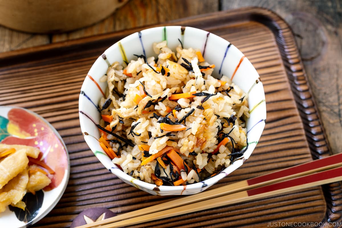 Un bol de riz contenant du riz Hijiki (Takikomi Gohan) servi avec des cornichons sur le côté.