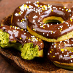 A wooden plate containing matcha donuts.