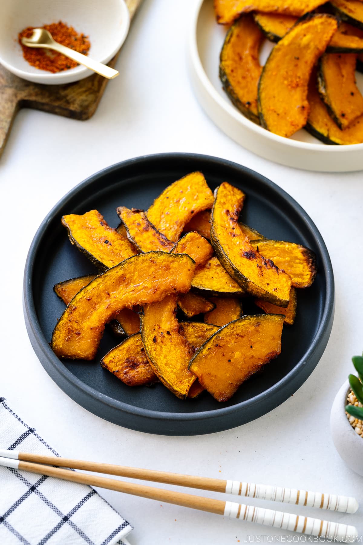 A black round ceramic plate containing roasted kabocha slices.