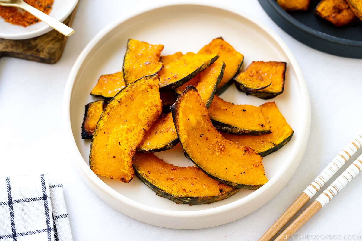 A white round ceramic plate containing roasted kabocha slices.