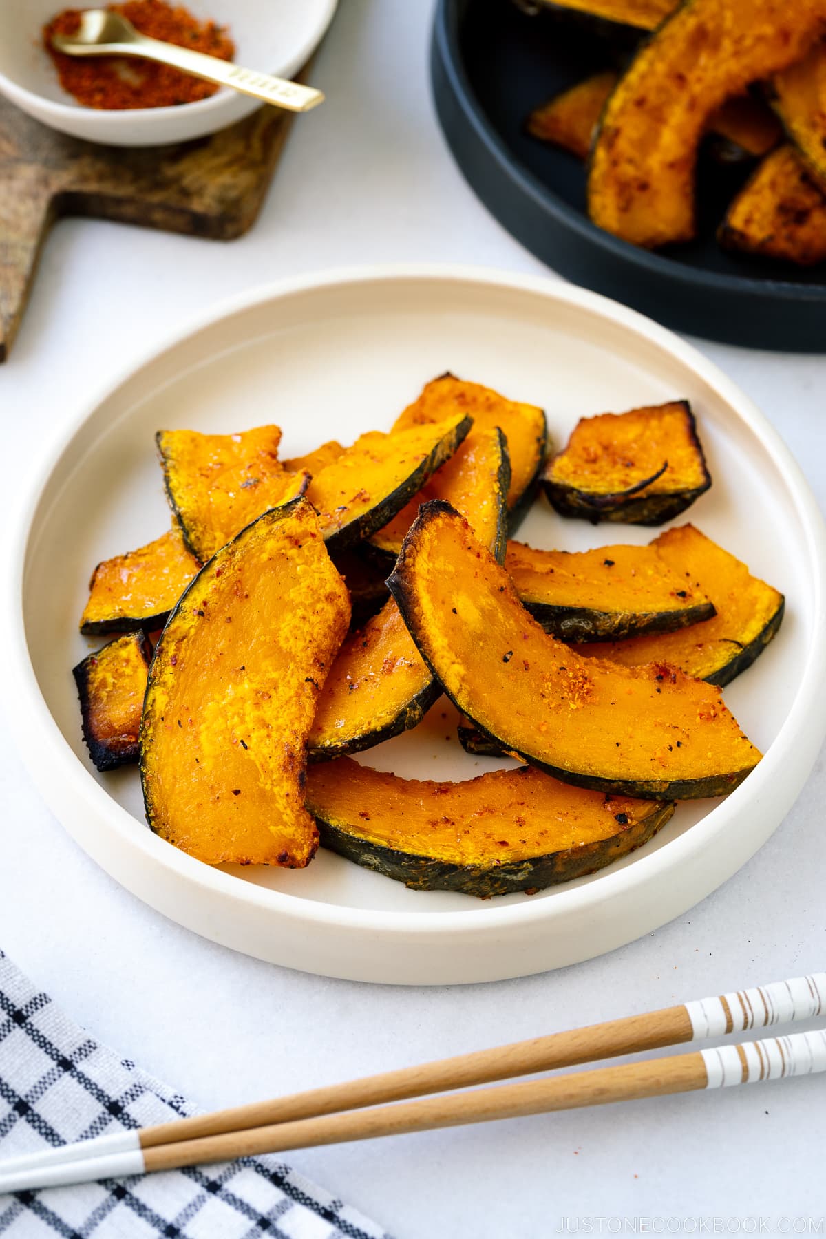 A white round ceramic plate containing roasted kabocha slices.